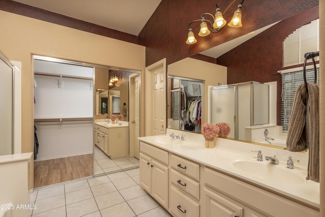 bathroom with tile patterned floors, a notable chandelier, a stall shower, and a sink