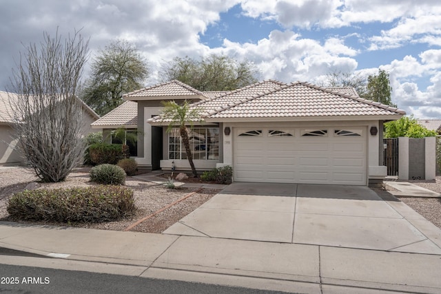 view of front of property featuring a tiled roof, an attached garage, driveway, and stucco siding