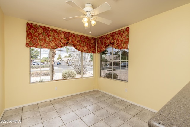 unfurnished dining area with light tile patterned floors, a ceiling fan, and baseboards