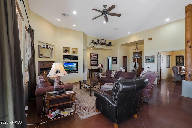 living room featuring a fireplace, built in features, and ceiling fan