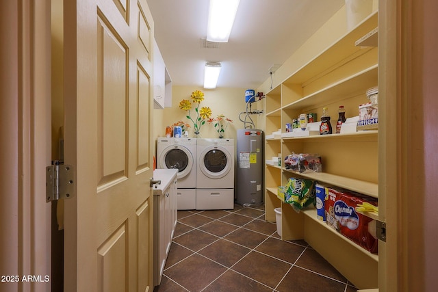 clothes washing area featuring washing machine and clothes dryer, water heater, and dark tile patterned flooring