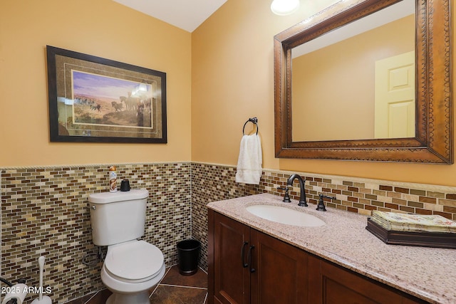 bathroom featuring tile patterned flooring, vanity, toilet, and tile walls