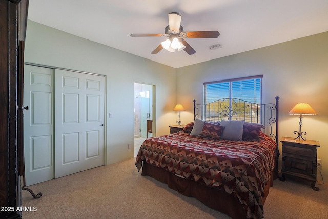 carpeted bedroom with ceiling fan, a closet, and ensuite bath