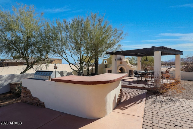 view of patio / terrace with a bar, an outdoor fireplace, and exterior kitchen