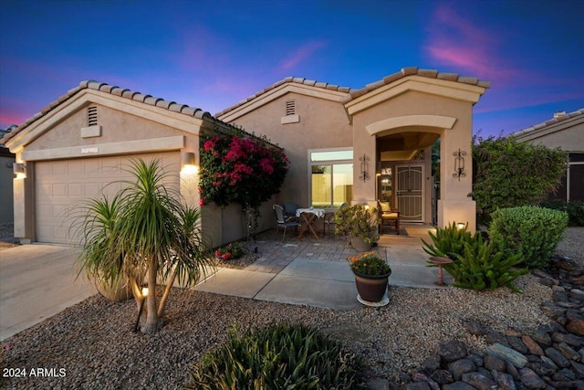 mediterranean / spanish-style house with a garage and a patio