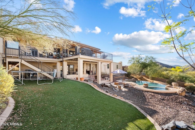 rear view of house with a patio area, a balcony, and a swimming pool with hot tub