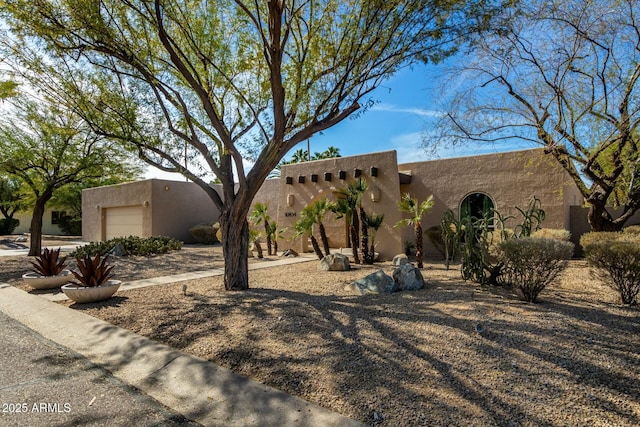 pueblo-style house with a garage and stucco siding