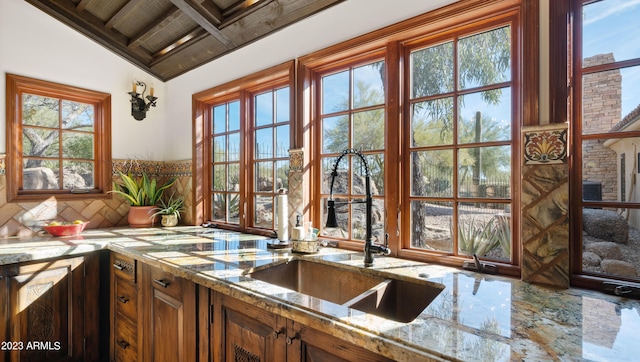 kitchen with light stone counters, sink, a wealth of natural light, and vaulted ceiling