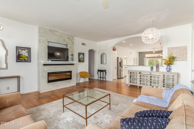 living room with a premium fireplace, a chandelier, and light wood-type flooring