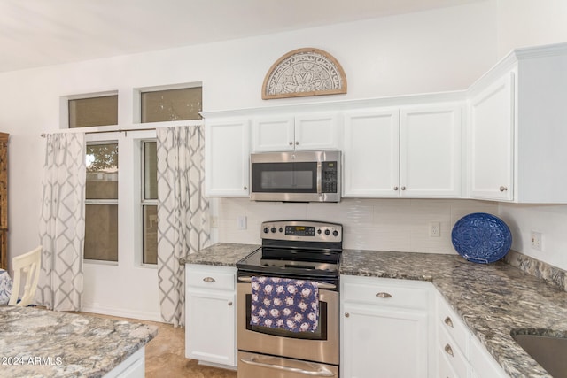 kitchen featuring appliances with stainless steel finishes, tasteful backsplash, white cabinets, and dark stone counters