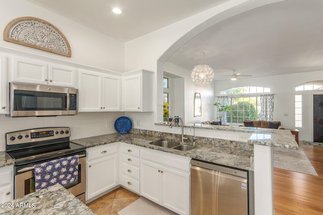 kitchen with appliances with stainless steel finishes, kitchen peninsula, white cabinetry, and sink