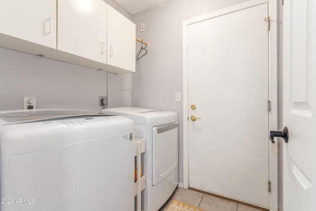 laundry area featuring washer and clothes dryer, light tile patterned floors, and cabinets