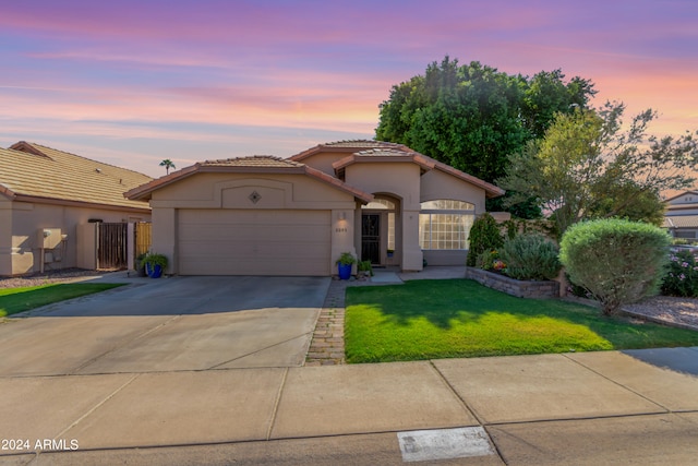 mediterranean / spanish home with a lawn and a garage