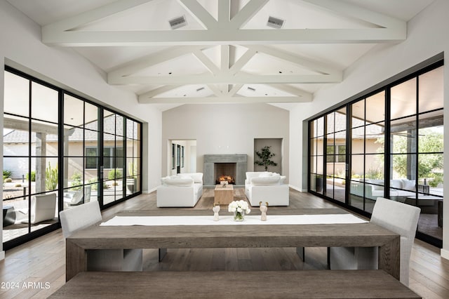 dining room with a premium fireplace, high vaulted ceiling, hardwood / wood-style floors, and beam ceiling