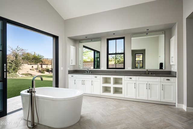 bathroom featuring vanity, vaulted ceiling, and a tub