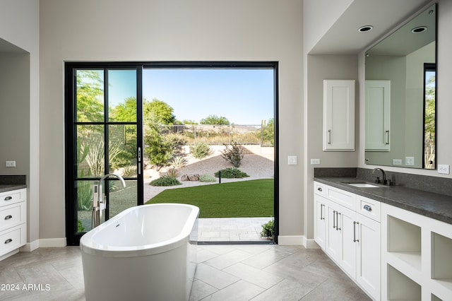 bathroom featuring tile patterned floors, a washtub, plenty of natural light, and vanity