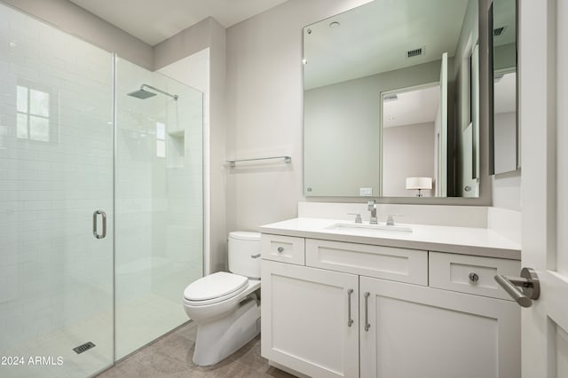 bathroom featuring tile patterned flooring, toilet, a shower with door, and vanity