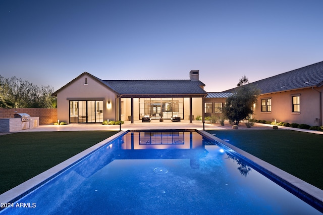 pool at dusk featuring a grill, a yard, and a patio