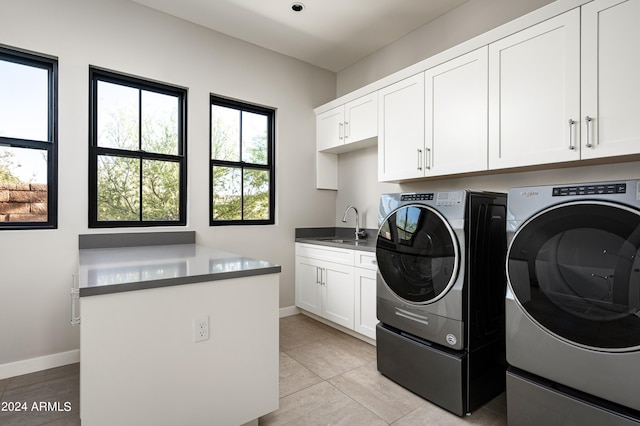 laundry room featuring washer and clothes dryer, light tile patterned flooring, cabinets, and sink