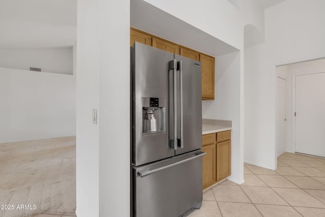 kitchen with high vaulted ceiling, light tile patterned flooring, high end fridge, light countertops, and brown cabinets