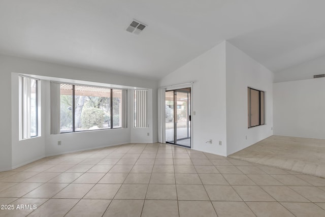 empty room featuring visible vents, light tile patterned flooring, and vaulted ceiling