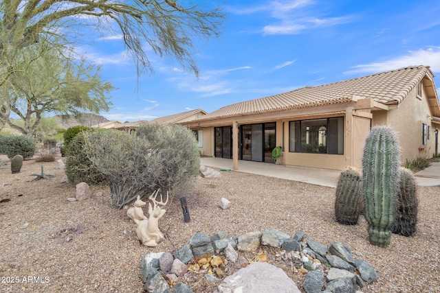 back of property featuring a patio area, stucco siding, and a tiled roof