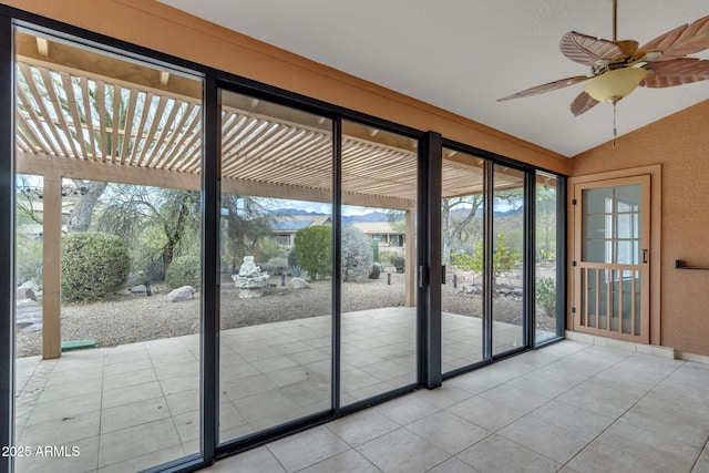 doorway to outside featuring tile patterned floors, a ceiling fan, and vaulted ceiling