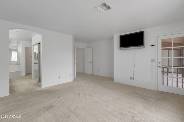 carpeted empty room with arched walkways and visible vents