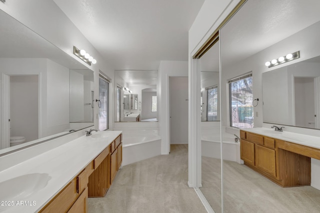 bathroom with a sink, toilet, a bath, and double vanity