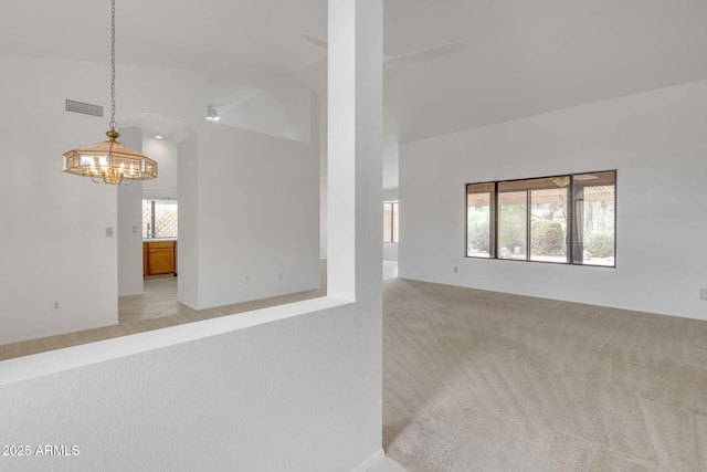 spare room featuring visible vents, light carpet, a notable chandelier, and high vaulted ceiling