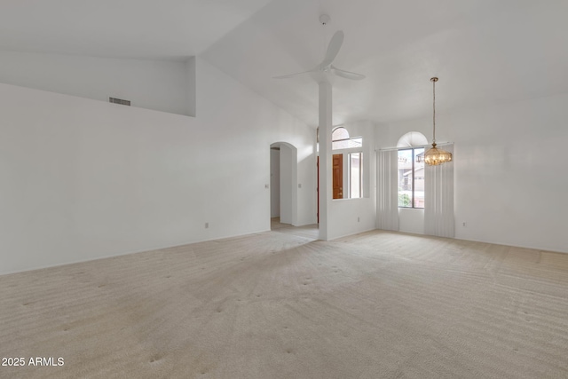 unfurnished room featuring visible vents, light carpet, ceiling fan with notable chandelier, arched walkways, and high vaulted ceiling