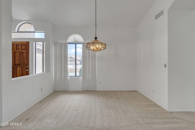 empty room featuring a chandelier, carpet flooring, and visible vents