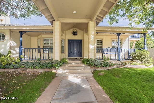 view of exterior entry featuring a lawn and a porch