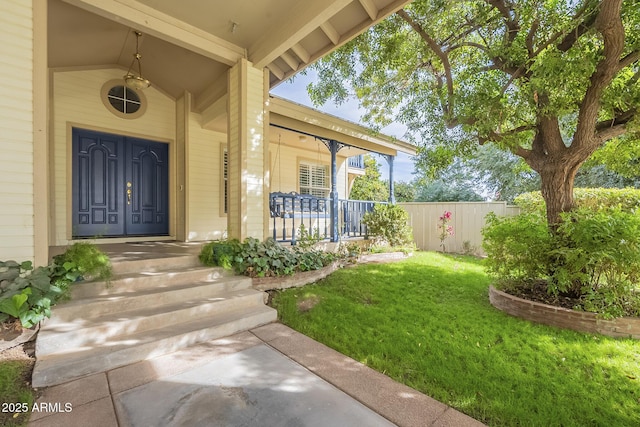 doorway to property featuring covered porch and a yard