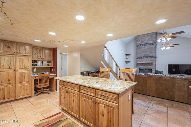 kitchen with a center island, light tile patterned flooring, built in desk, and a fireplace