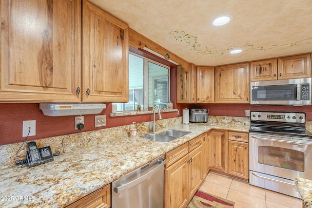 kitchen with light stone countertops, sink, light tile patterned floors, and stainless steel appliances