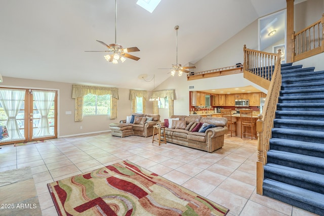 living room featuring french doors, a skylight, ceiling fan, high vaulted ceiling, and light tile patterned flooring