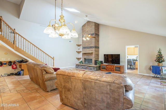 living room with a fireplace, light tile patterned floors, ceiling fan with notable chandelier, and high vaulted ceiling