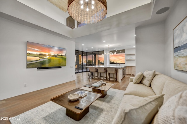 living room featuring a towering ceiling, a notable chandelier, and light hardwood / wood-style floors