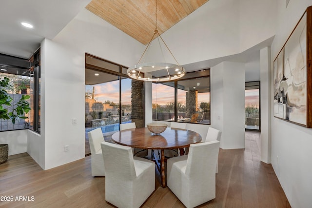 dining space with vaulted ceiling, wooden ceiling, an inviting chandelier, and light hardwood / wood-style floors