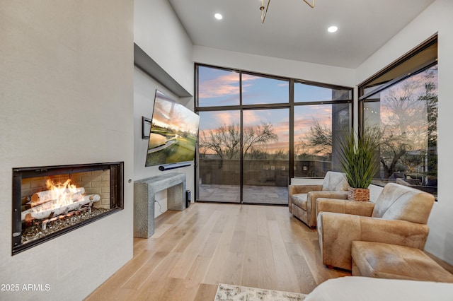 living room with a tile fireplace and light wood-type flooring