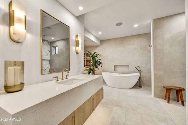 bathroom with tile walls, vanity, and a bathtub