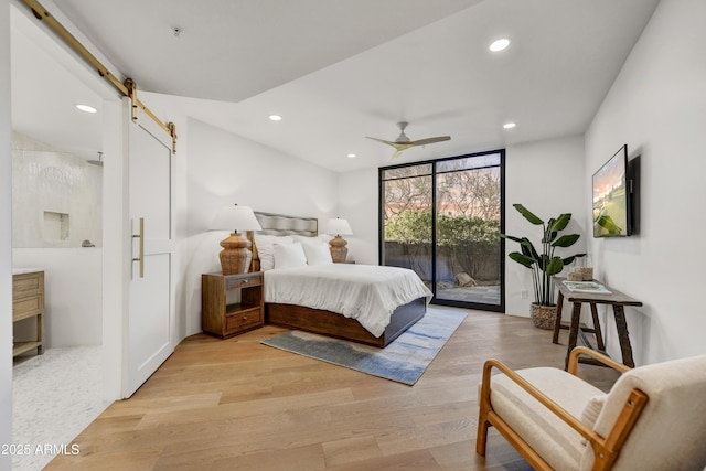 bedroom with a wall of windows, ceiling fan, access to exterior, light hardwood / wood-style floors, and a barn door