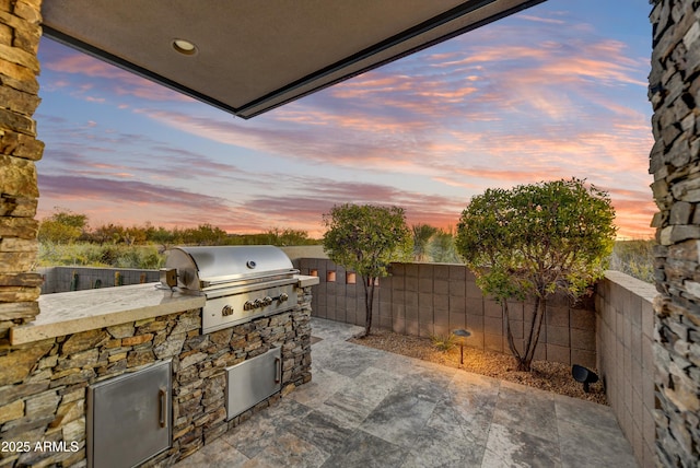 patio terrace at dusk featuring area for grilling and grilling area