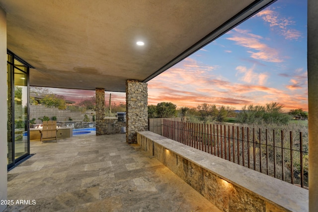 patio terrace at dusk featuring area for grilling