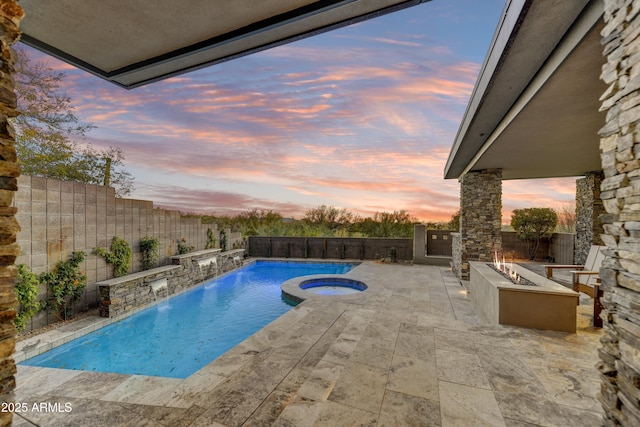 pool at dusk with an in ground hot tub, a patio area, and a fire pit