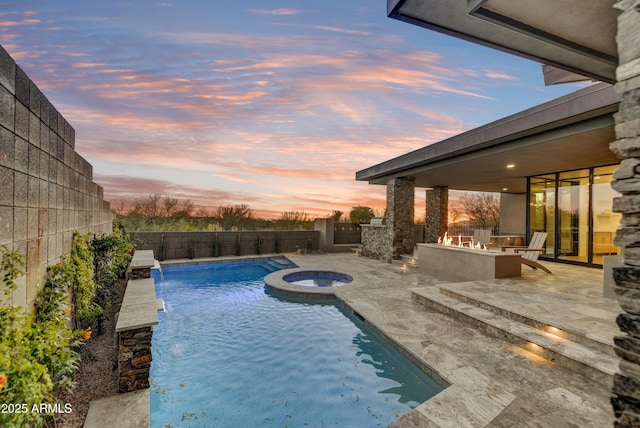 pool at dusk featuring an in ground hot tub, pool water feature, a patio, and an outdoor fire pit