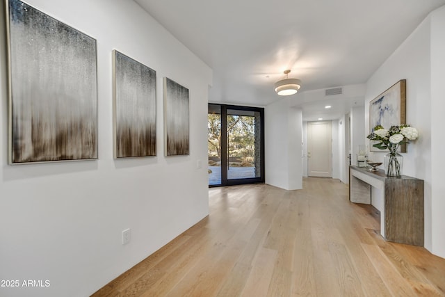 hall featuring a wall of windows and light hardwood / wood-style floors