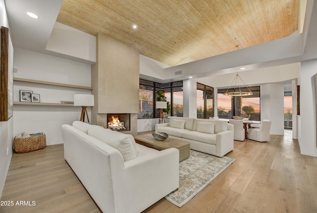 living room with light hardwood / wood-style flooring, wooden ceiling, vaulted ceiling, and a multi sided fireplace