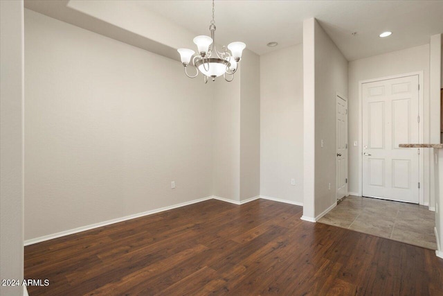 unfurnished room featuring a notable chandelier and dark hardwood / wood-style floors